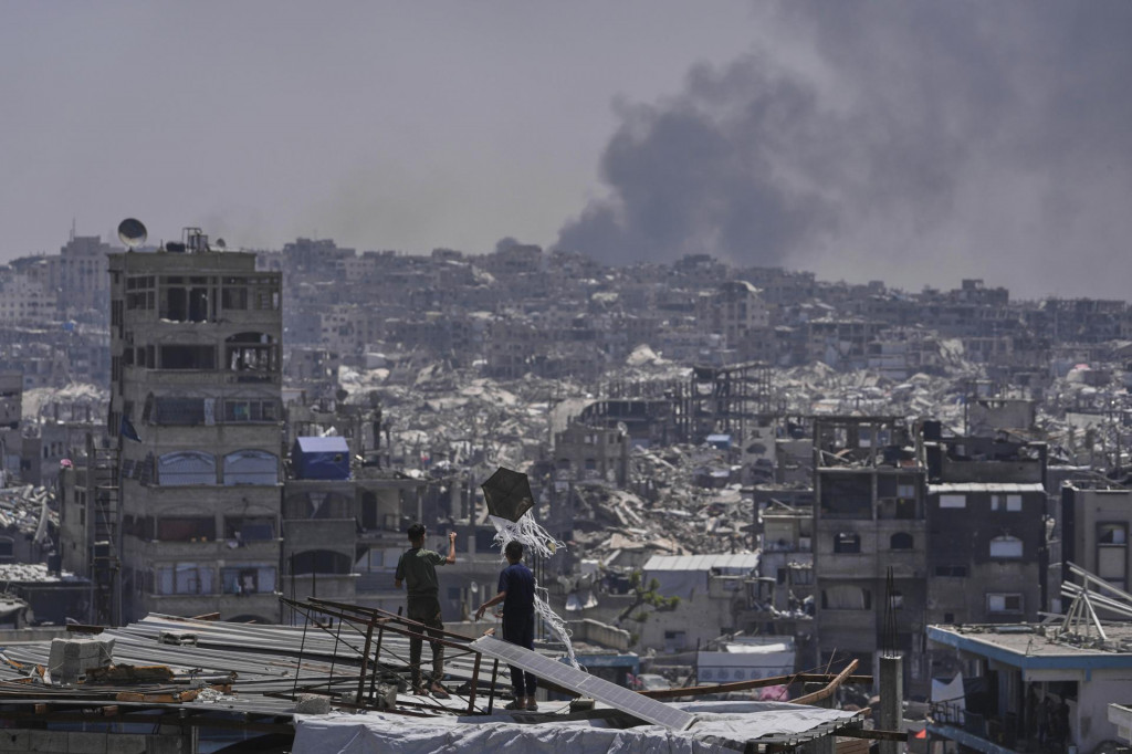 Palestínčania sa pozerajú ako dym stúpa pri explózii po izraelskom bombardovaní Pásma Gazy neďaleko mesta Džabalia, na severe Pásma Gazy. FOTO: TASR/AP