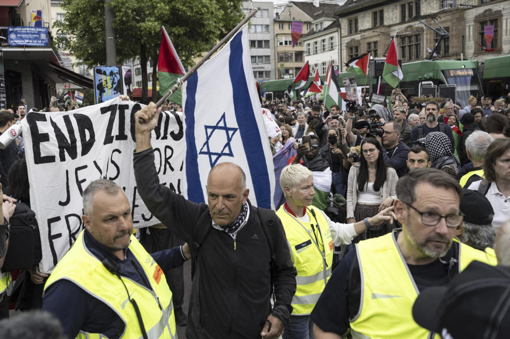 Muž s izraelskou vlajkou stojí v blízkosti propalestínskych demonštrantov pred začiatkom finále piesňovej súťaže Eurovízia vo švajčiarskom Bazileji. FOTO: TASR/AP