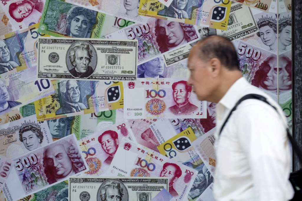 Muž prechádza okolo reklamy propagujúcej čínsky renminbi (RMB) alebo juan, americký dolár a euro v zmenárni v Hongkongu v Číne 13. augusta 2015. FOTO: REUTERS