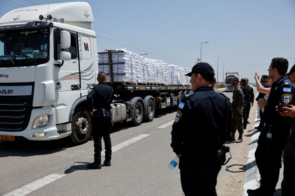 Príslušníci izraelských bezpečnostných síl stoja pri nákladných autách s humanitárnou pomocou. FOTO: Reuters