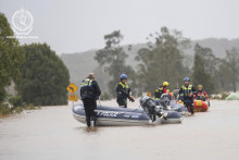 Záchranári sa brodia s nafukovacími člnmi cez zaplavenú ulicu v austrálskom meste Taree. FOTO: TASR/AP
