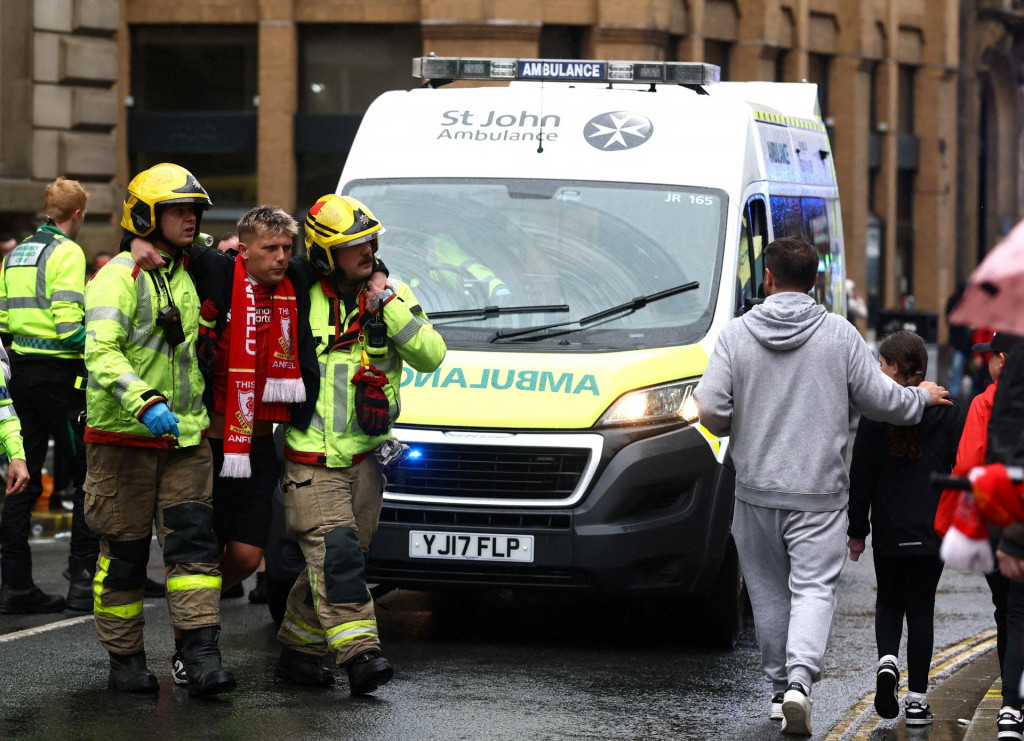 Záchranári odvádzajú fanúšika po incidente s autom a fanúšikmi počas prehliadky víťazstva. FOTO: Reuters