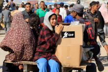 Ľudia sa veziu na vozíku, zatiaľ čo sa Palestínčania hľadajúci pomoc zhromažďujú neďaleko miesta distribúcie pomoci, ktoré prevádzkuje Humanitárna nadácia pre Gazu podporovaná USA, v Rafahu v južnom pásme Gazy. FOTO: REUTERS