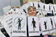 Demonštrantka drží transparenty reprezentujúce obete počas protestu pred verdiktom súdu v kauze lekára na dôchodku obvineného zo znásilnenia a sexuálneho napadnutia 299 obetí vo francúzskom meste Vannes v stredu 28. mája 2025. FOTO TASR/AP
