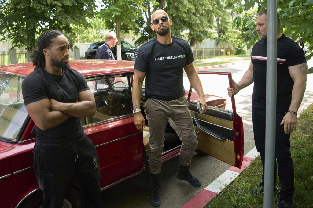 Kontroverzný influencer Andrew Tate vystupuje z automobilu Lada počas príchodu na policajnú stanicu v Bukurešti. FOTO: TASR/AP