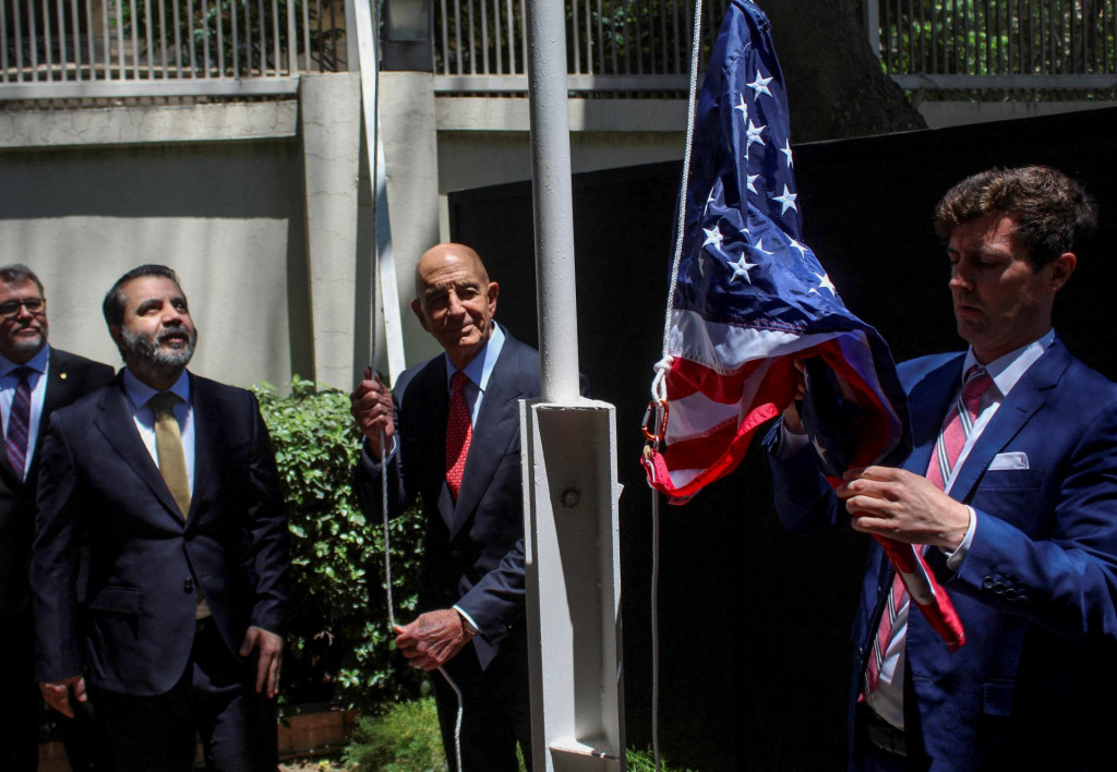Sýrsky minister zahraničných vecí Asaad Hassan al-Šíbání stojí vedľa amerického vyslanca pre Sýriu Thomasa Barracka, keď vztýčuje americkú vlajku pred rezidenciou amerického veľvyslanca v Damasku. FOTO: Reuters
