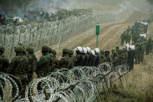 Poľskí vojaci a policajti sledujú migrantov na poľsko-bieloruskej hranici neďaleko Kuznice v Poľsku. FOTO: REUTERS