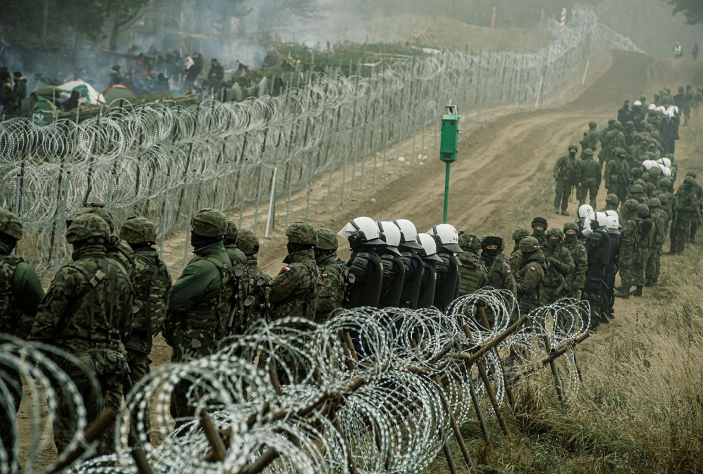 Poľskí vojaci a policajti sledujú migrantov na poľsko-bieloruskej hranici neďaleko Kuznice v Poľsku. FOTO: REUTERS