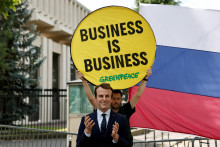 Aktivista Greenpeace drží transparent s nápisom „Biznis je biznis“ vedľa voskovej sochy francúzskeho prezidenta Emmanuela Macrona pred ruským veľvyslanectvom. FOTO: Reuters