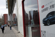 Ľudia prechádzajú okolo predajne výrobcu elektrických vozidiel Tesla v Pekingu v Číne 24. marca 2025. FOTO: REUTERS