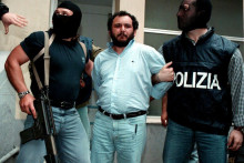 Polícia sprevádza popredného mafiánskeho utečenca Giovaniho Bruscu, keď odchádza z policajného riaditeľstva v Palerme, aby bol prevezený do väznice s maximálnym stupňom stráženia. (23. mája 1992). FOTO: Reuters