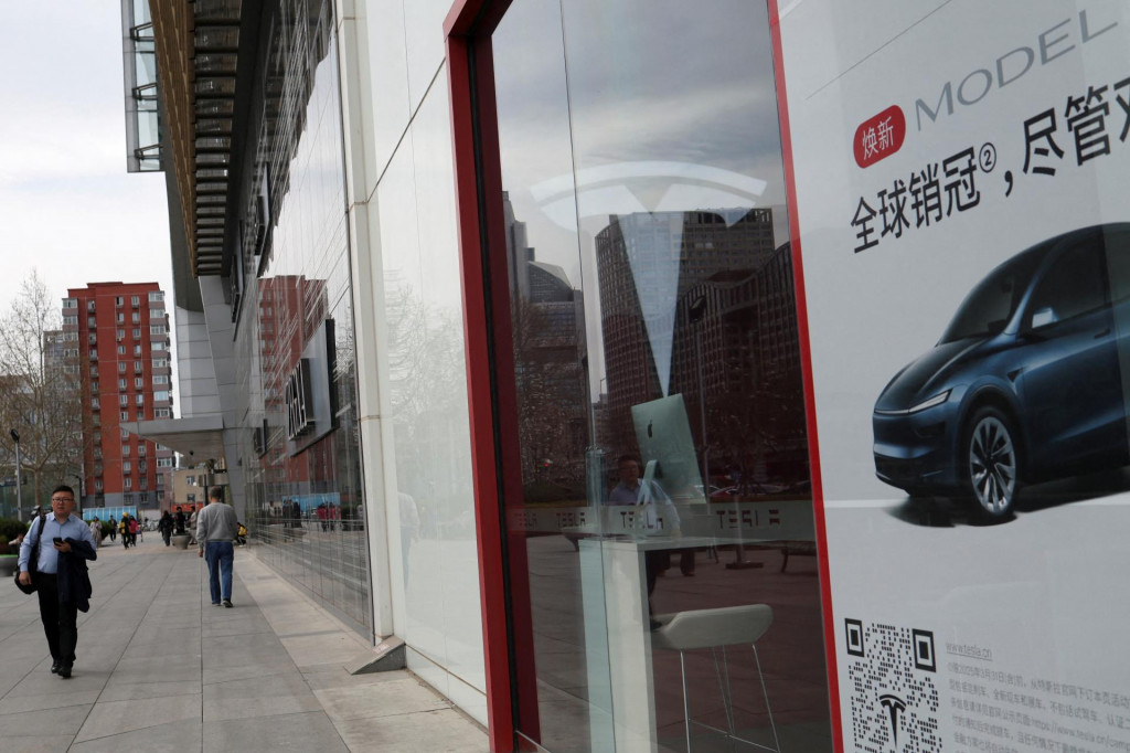 Ľudia prechádzajú okolo predajne výrobcu elektrických vozidiel Tesla v Pekingu v Číne 24. marca 2025. FOTO: REUTERS