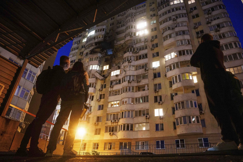 Ľudia sa pozerajú na viacposchodovú obytnú budovu po dronovom útoku ruskej armády na ukrajinské hlavné mesto Kyjev. FOTO: TASR/AP
