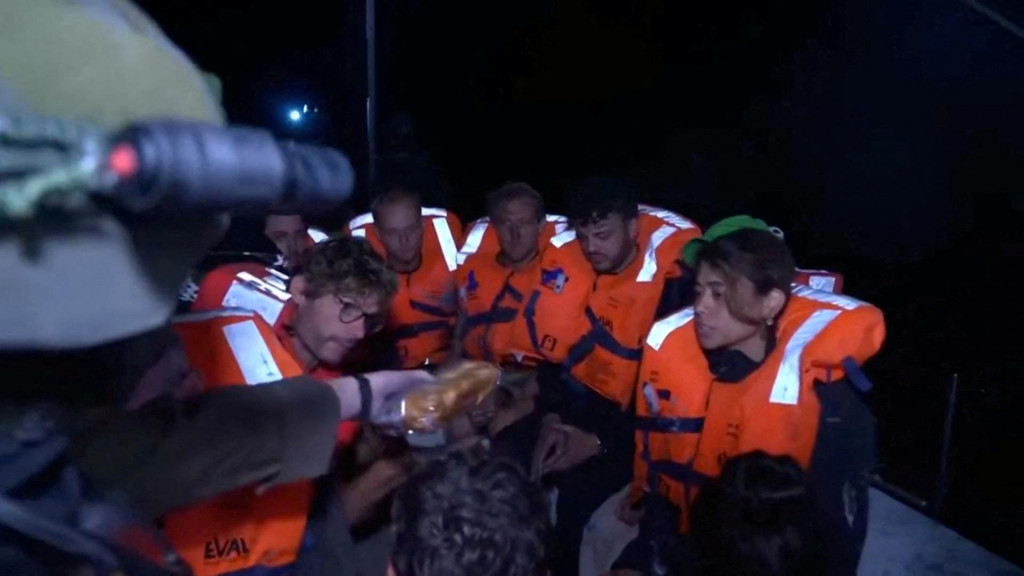 Izraelský vojak podáva jedlo ľuďom na palube jachty „Madleen“ plaviacej sa pod britskou vlajkou smerujúcej do Gazy po tom, čo izraelské sily vstúpili na palubu lode. FOTO: Reuters/Izraelské ministerstvo zahraničných vecí