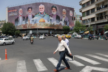 Iránci kráčajú vedľa billboardu s fotografiou zosnulého vodcu Hamasu Ismáíla Haníju, vysokého iránskeho vojenského veliteľa generála Kásema Solejmáního, zosnulého vodcu libanonského Hizballáhu Sajjída Hasana Nasralláha a zosnulého vodcu Hamasu Jahju as-Sinwara na ulici v Teheráne v Iráne. FOTO: Reuters/WANA