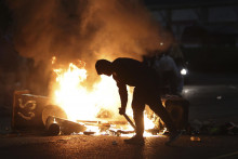 Demonštrant prehrabáva horiacu barikádu počas výtržností v severoírskom meste Ballymena. FOTO: TASR/AP
