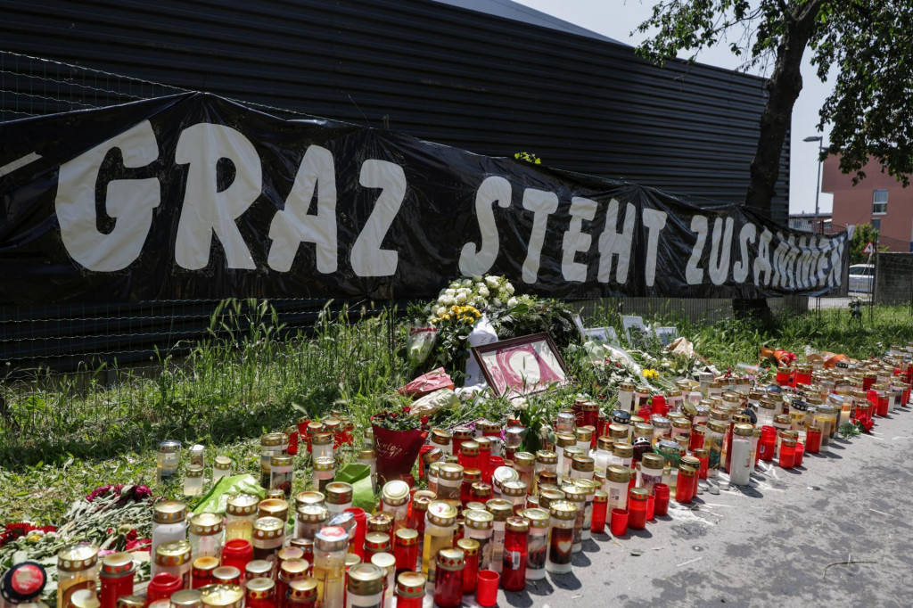 Kvety, sviečkynn a transparent s nápisom „Graz stojí spolu“. FOTO: Reuters
