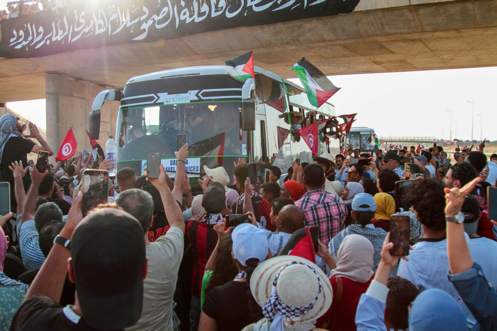 Ľudia vítajú aktivistov v autobusoch, ktorí vyrazili po súši z tuniského hlavného mesta Tunis k egyptským hraniciam s Pásmom Gazy, aby tak prejavili solidaritu s obyvateľmi tejto palestínskej enklávy. FOTO: TASR/AP