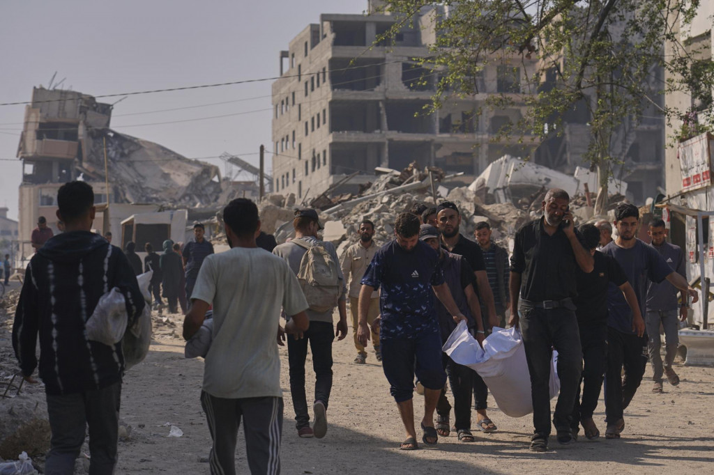 Palestínčania vynášajú telo osoby, ktorá zahynula v noci počas izraelských leteckých útokov v Pásme Gazy na ľudí čakajúcich na humanitárnu pomoc, neďaleko nemocnice Al-Šifa v meste Gaza. FOTO: TASR/AP