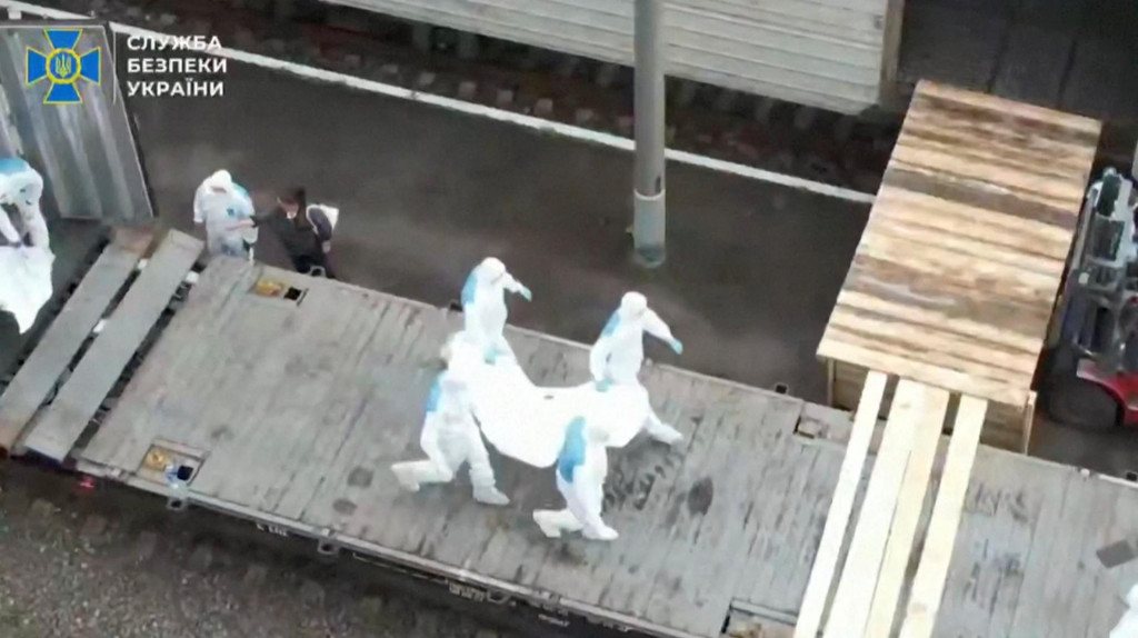 Ľudia v ochranných oblekoch nesú na neznámom mieste  pozostatky ukrajinských vojakov prijatých z Ruska. FOTO: REUTERS