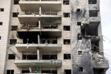 Záchranári a bezpečnostní pracovníci pracujú v zasiahnutej obytnej budove po raketovom útoku z Iránu na Izrael. FOTO: Reuters