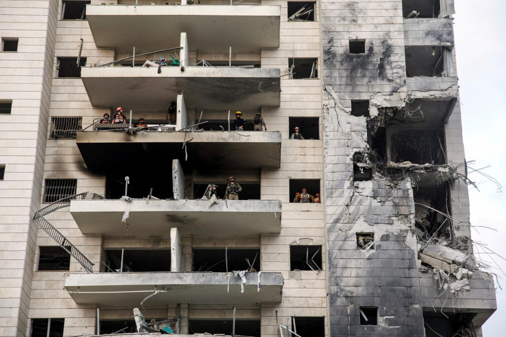 Záchranári a bezpečnostní pracovníci pracujú v zasiahnutej obytnej budove po raketovom útoku z Iránu na Izrael. FOTO: Reuters