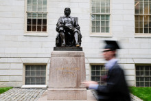 Študent prechádza okolo sochy Johna Harvarda v deň 374. promočných ceremónií na Harvardskej univerzite v Cambridge, Massachusetts, USA, 29. mája 2025. FOTO: REUTERS