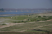 Ľudia kráčajú popri obrábanej pôde na vyschnutom koryte rieky Indus v Pakistane. FOTO: Reuters