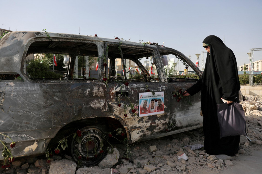 Žena sa pozerá na sanitku, ktorú na ulici v Teheráne zničili izraelské útoky. FOTO: Reuters/WANA