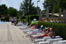 Návštevníci sa opaľujú pri bazénoch počas otvorenia letného kúpaliska v Trenčíne. FOTO: TASR/Martin Medňanský
