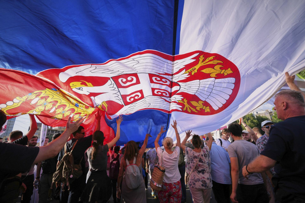 Ľudia kráčajú pod obrovskou srbskou vlajkou počas protivládneho zhromaždenia v Belehrade. FOTO: TASR/AP