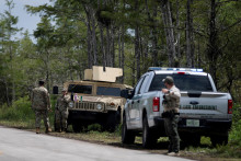 Príslušníci floridskej Národnej gardy stoja pri vchode na výcvikové a prechodné letisko Dade-Collier. FOTO: REUTERS