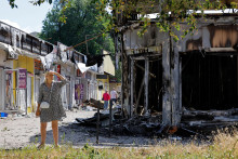 Žena stojí vedľa zničeného obchodu na trhu, ktorý bol v pondelok zasiahnutý ostreľovaním, ktoré miestne ruské úrady označili za ukrajinský vojenský útok. FOTO: REUTERS