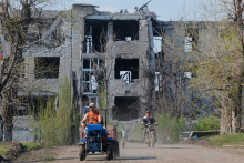 Muži na vozidlách neďaleko budovy zničenej počas rusko-ukrajinského konfliktu v Toškivke v Luhanskej oblasti. FOTO: REUTERS