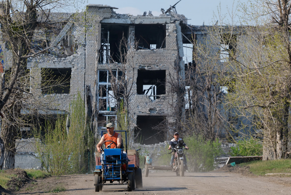 Muži na vozidlách neďaleko budovy zničenej počas rusko-ukrajinského konfliktu v Toškivke v Luhanskej oblasti. FOTO: REUTERS