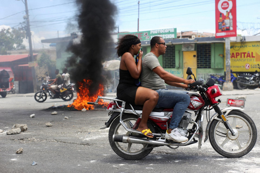 Motocyklista prechádza okolo horiacej barikády počas protestu proti násiliu páchanému gangmi v Port-au-Prince na Haiti. FOTO: Reuters