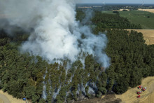 Hasiči hasia lesný požiar na okraji pola s obilím počas horúčav v Brandenburgu 2. júla 2025. FOTO: TASR/AP