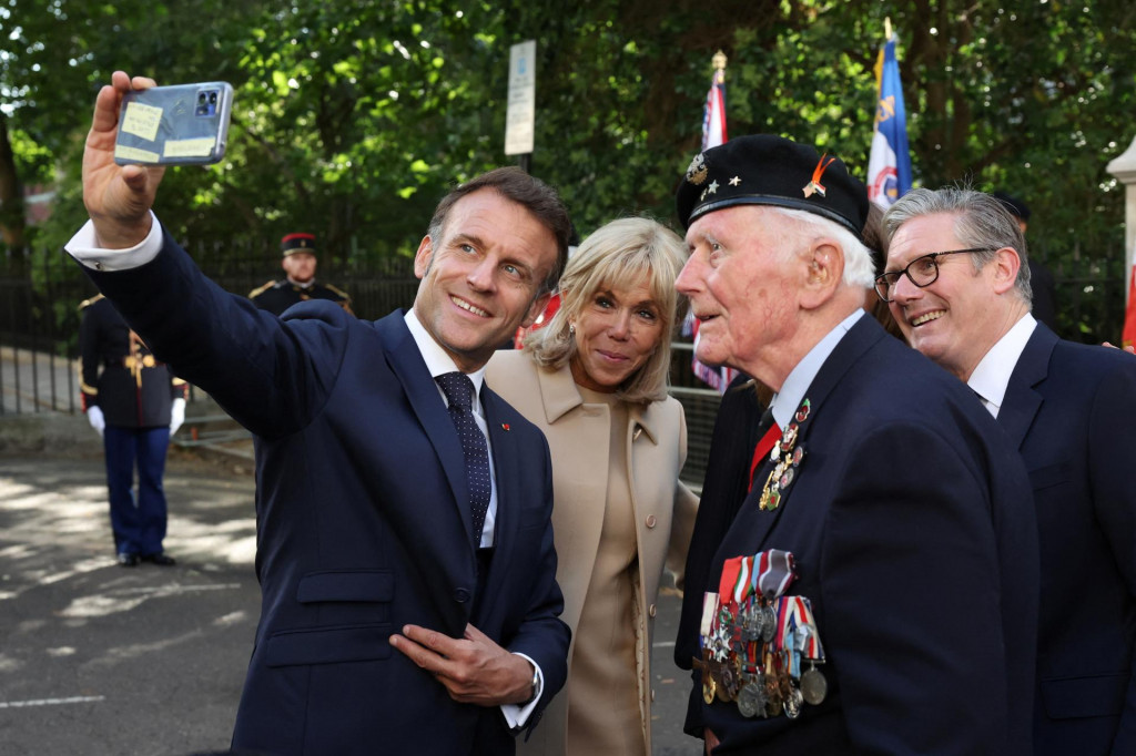Francúzsky prezident Emmanuel Macron si robí selfie so svojou manželkou Brigitte Macronovou, britským premiérom Keirom Starmerom a veteránom Eugeniusom Neadom. FOTO: Reuters