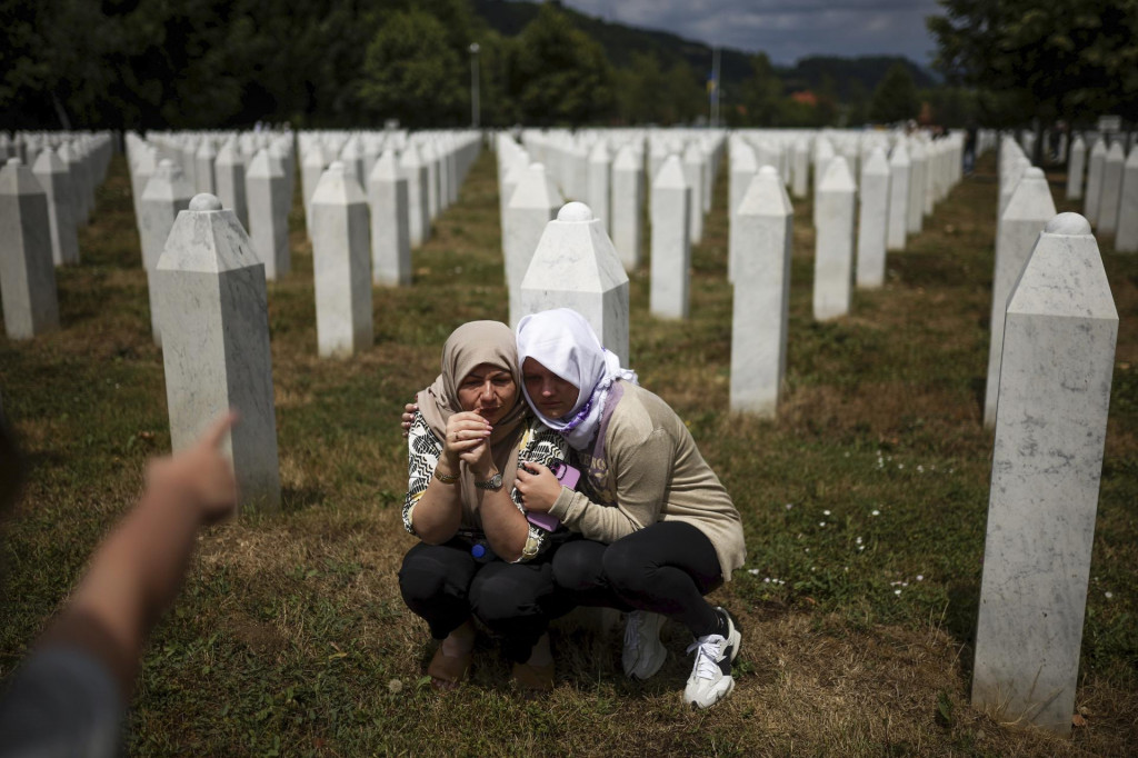 Rodinní príslušníci plačú pri hroboch svojich príbuzných, obetí srebrenickej genocídy na cintoríne v obci Počotari. FOTO: TASR/AP