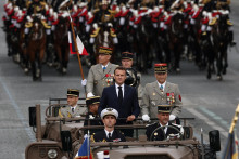 Francúzsky prezident Emmanuel Macron stojí vo veliteľskom aute s náčelníkom štábu francúzskych ozbrojených síl Thierrym Burkhardom počas ceremoniálu ku Dňu dobytia Bastily. FOTO: Reuters