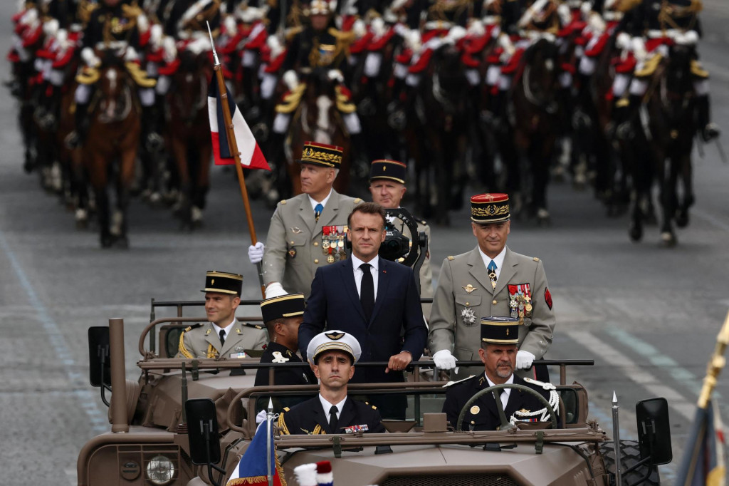 Franc&uacute;zsky prezident Emmanuel Macron stoj&iacute; vo veliteľskom aute s n&aacute;čeln&iacute;kom &scaron;t&aacute;bu franc&uacute;zskych ozbrojen&yacute;ch s&iacute;l Thierrym Burkhardom počas ceremoni&aacute;lu ku Dňu dobytia Bastily. FOTO: Reuters