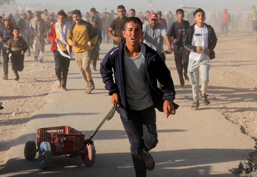 Archívna snímka Palestínčanov kráčajjúcich si po humanitárnu pomoc. FOTO: REUTERS