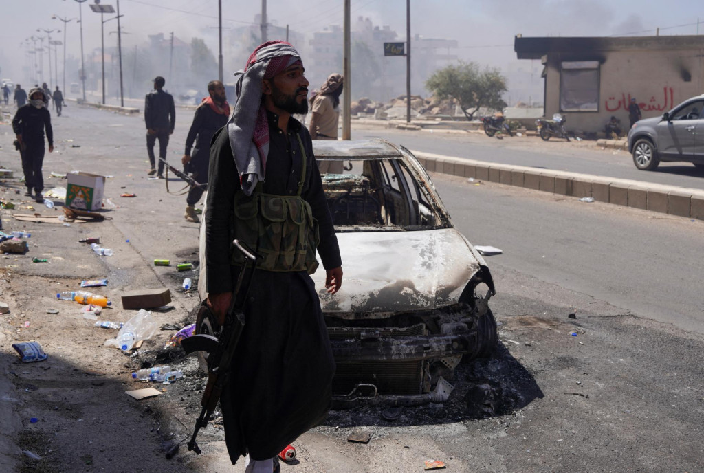 Beduínsky bojovník stojí pri poškodenom aute. FOTO: Reuters