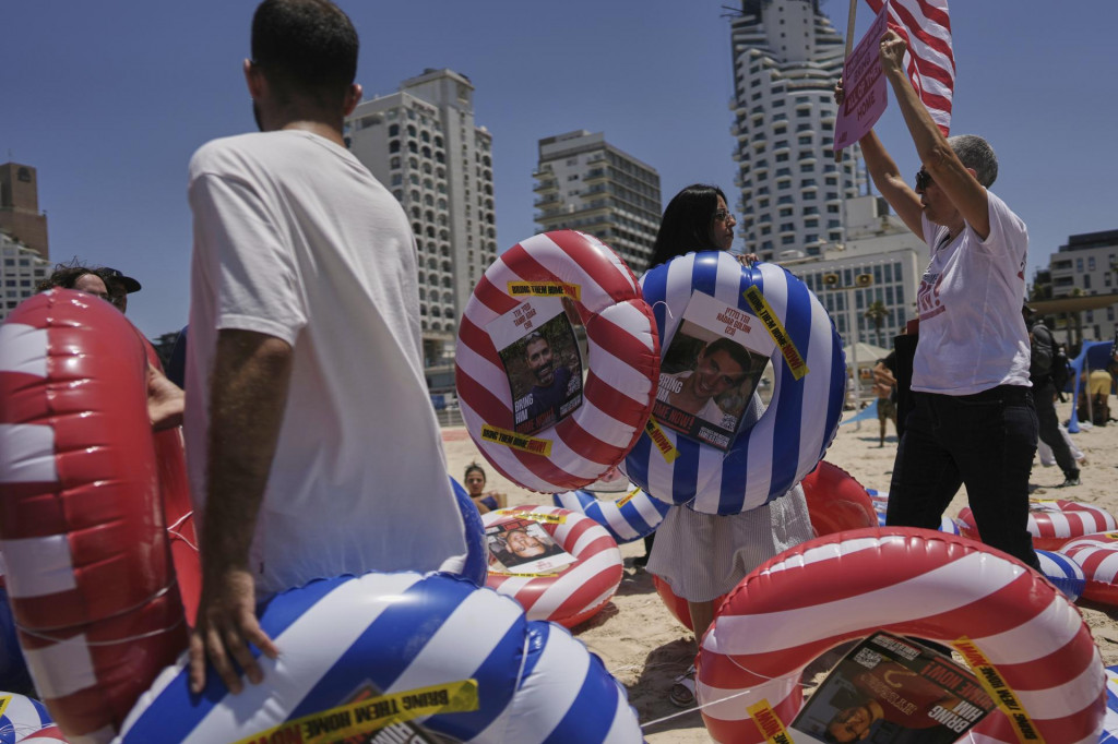 Demonštranti držia reťaz s nafukovacími kolesami s fotografiami izraelských rukojemníkov zadržiavaných Hamasom v Pásme Gazy vyzývajúce na ich prepustenie a skončenie vojny v Gaze. FOTO: TASR/AP