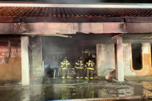 Hasiči zasahuj&uacute; pri požiari po n&aacute;raze auta do budovy po&scaron;ty. FOTO: TASR/AP