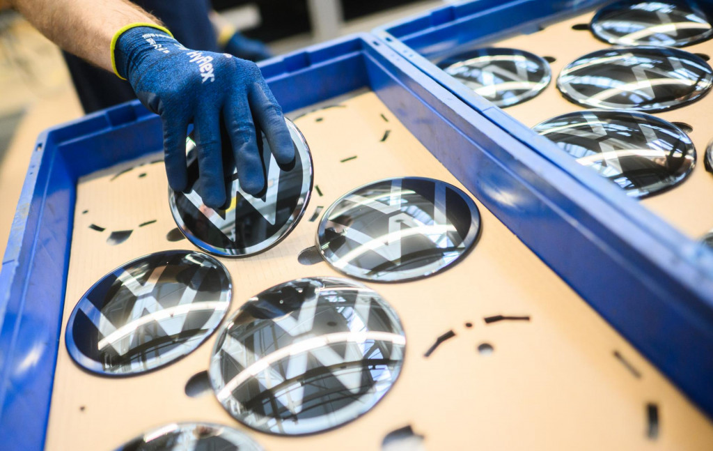 Zamestnanec v centrále Volkswagenu drží logo VW určené na inštaláciu do nového auta v nemeckom Wolfsburgu. FOTO: TASR/DPA