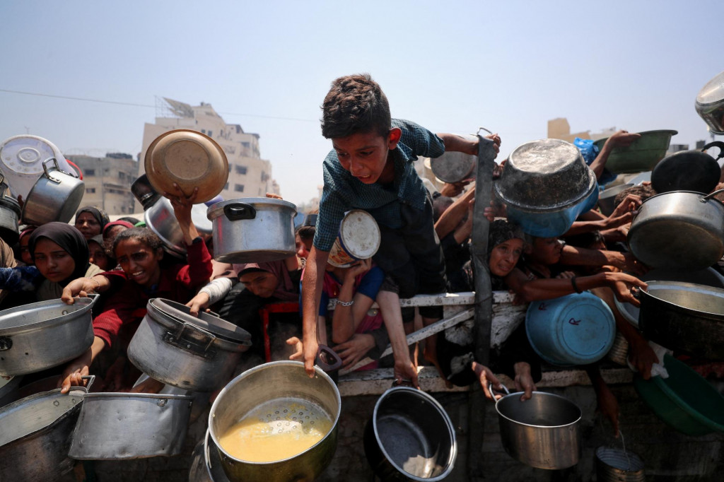 Palestínčania čakajú na jedlo z charitatívnej kuchyne v meste Gaza. FOTO: Reuters