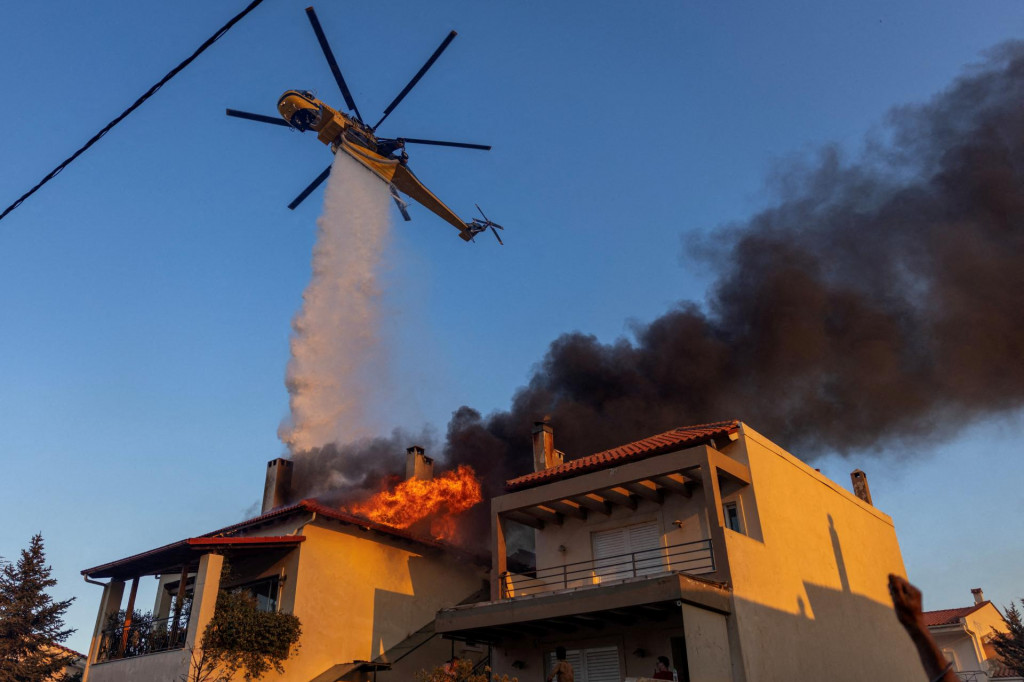 Hasičský vrtuľník zasahuje proti požiaru v dedine Kryoneri neďaleko Atén. FOTO: Reuters