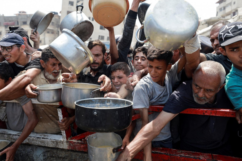 Palestínčania sa zhromažďujú, aby si prevzali jedlo z charitatívnej kuchyne. FOTO: Reuters