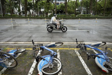 Motocyklista jazdí v daždi okolo spadnutých bicyklov po búrke Wipha v Hanoji. FOTO: TASR/AP